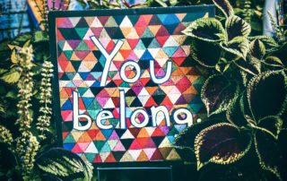 A colorful image surrounded by green vines that says, "You Belong"
