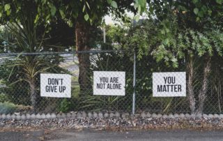 Signs on a fence that say don't give up and you matter
